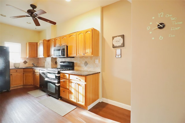 kitchen with tasteful backsplash, baseboards, black appliances, and wood finished floors