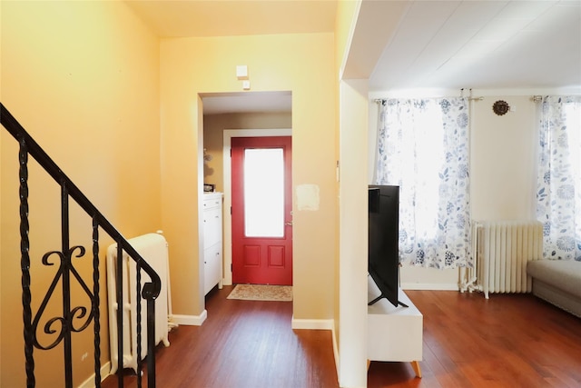 entryway featuring radiator heating unit, stairs, baseboards, and dark wood-style flooring