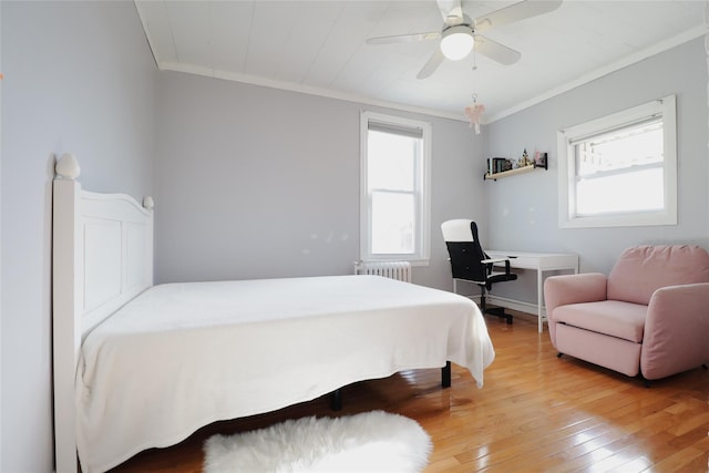 bedroom with radiator, light wood-type flooring, ornamental molding, and ceiling fan