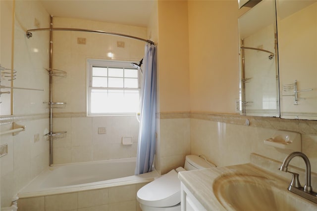 bathroom with tiled shower / bath, toilet, vanity, and tile walls