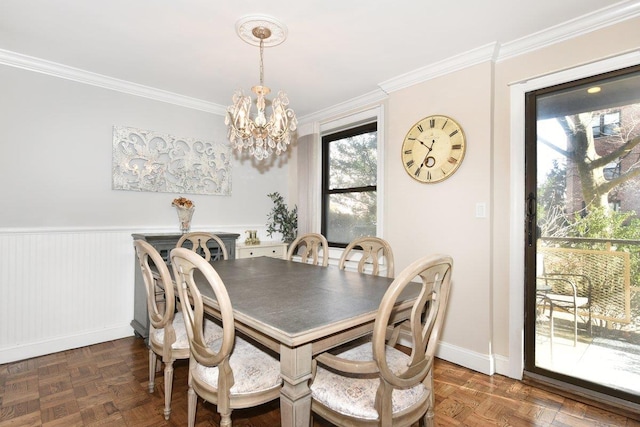 dining space featuring ornamental molding, a wainscoted wall, a notable chandelier, and baseboards