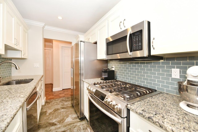 kitchen with light stone countertops, white cabinetry, stainless steel appliances, and a sink