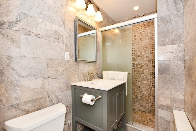 bathroom with toilet, recessed lighting, vanity, tile walls, and a stall shower