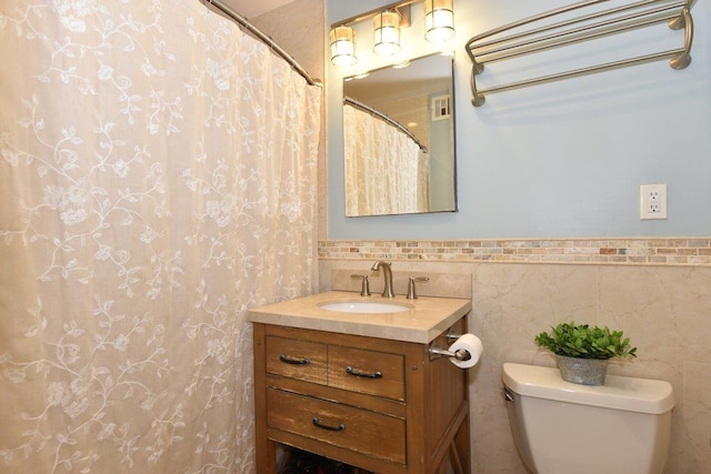 full bath featuring toilet, vanity, visible vents, and tile walls