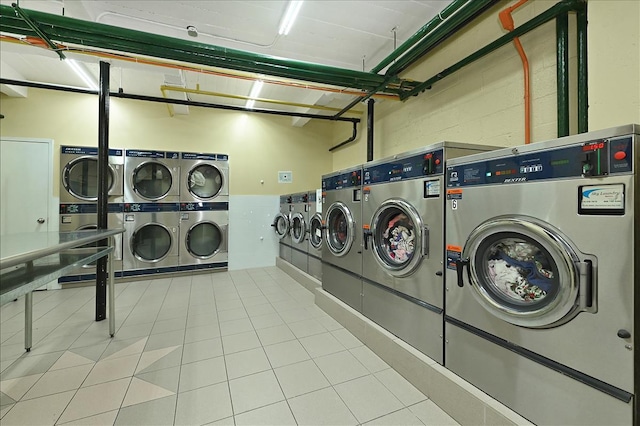 common laundry area featuring stacked washer and dryer, tile patterned flooring, a garage, and washing machine and clothes dryer