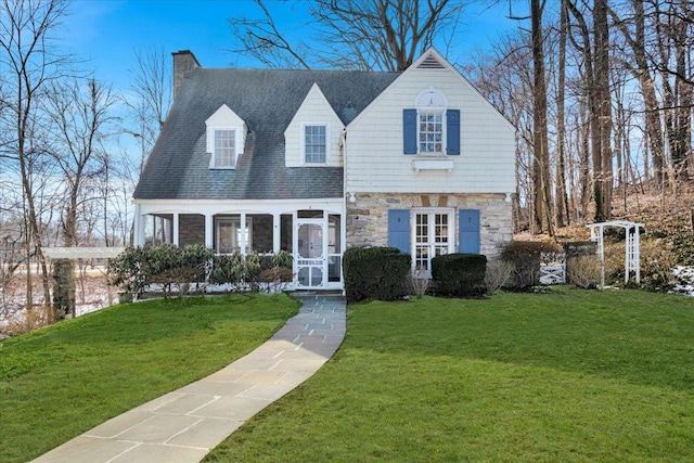 view of front of property featuring stone siding, a chimney, and a front lawn