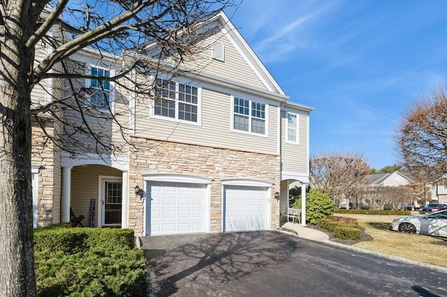 view of front of home featuring aphalt driveway, stone siding, and a garage