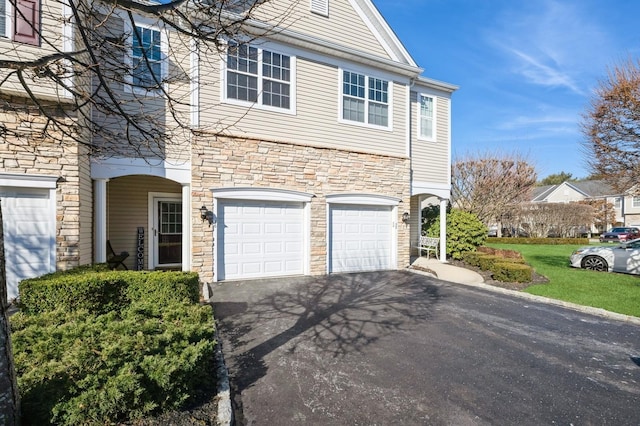 view of front of property with a garage, driveway, a front lawn, and stone siding