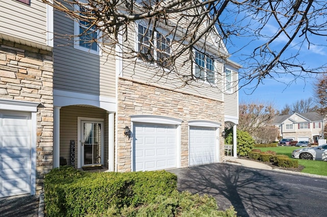 exterior space with a garage, stone siding, and driveway