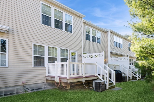 back of property featuring a deck, cooling unit, and a yard