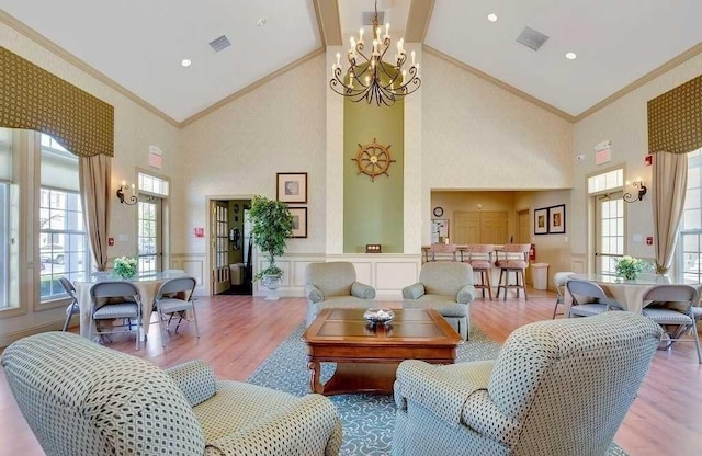 living room with crown molding, a decorative wall, wainscoting, wood finished floors, and high vaulted ceiling