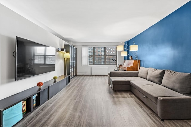 living area featuring plenty of natural light, radiator heating unit, and wood finished floors