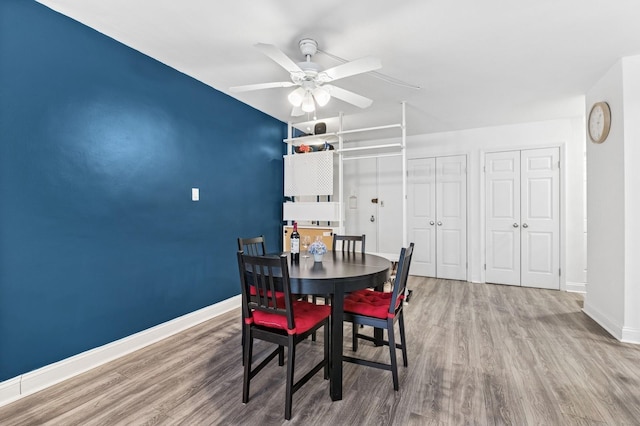 dining space featuring a ceiling fan, baseboards, and wood finished floors