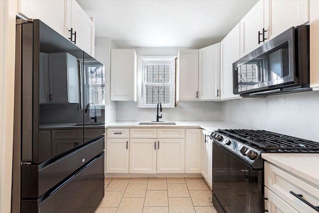 kitchen featuring light countertops, a sink, black appliances, and white cabinetry