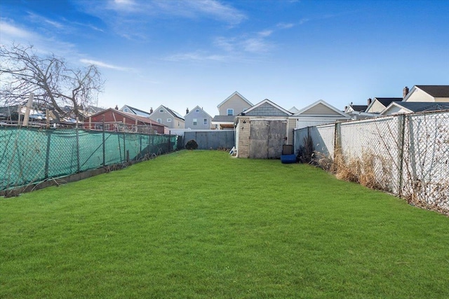 view of yard with a storage shed, an outbuilding, a fenced backyard, and a residential view