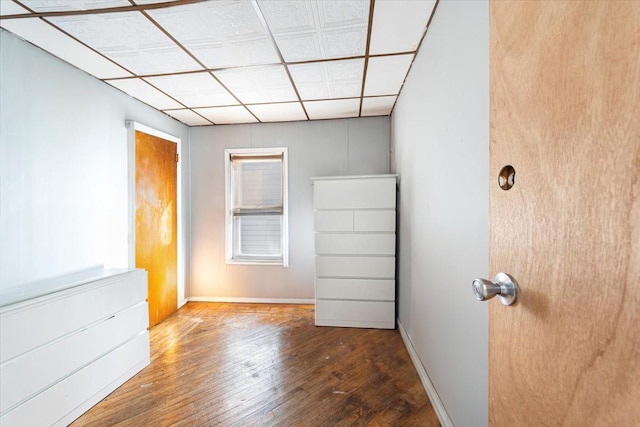 unfurnished room featuring baseboards, a drop ceiling, and wood finished floors