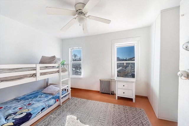 bedroom with light wood-style flooring, radiator heating unit, and a ceiling fan