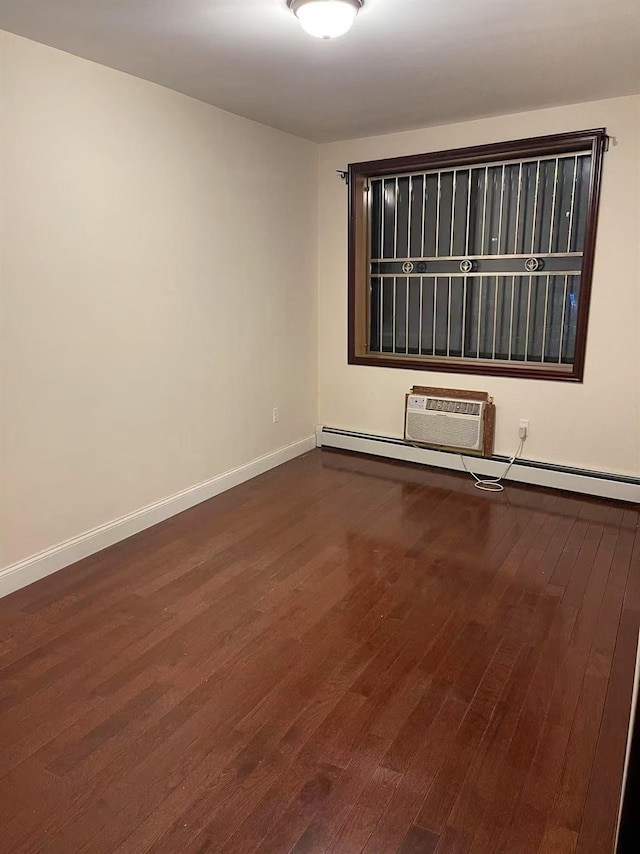 empty room featuring baseboard heating, dark wood-style flooring, a wall unit AC, and baseboards