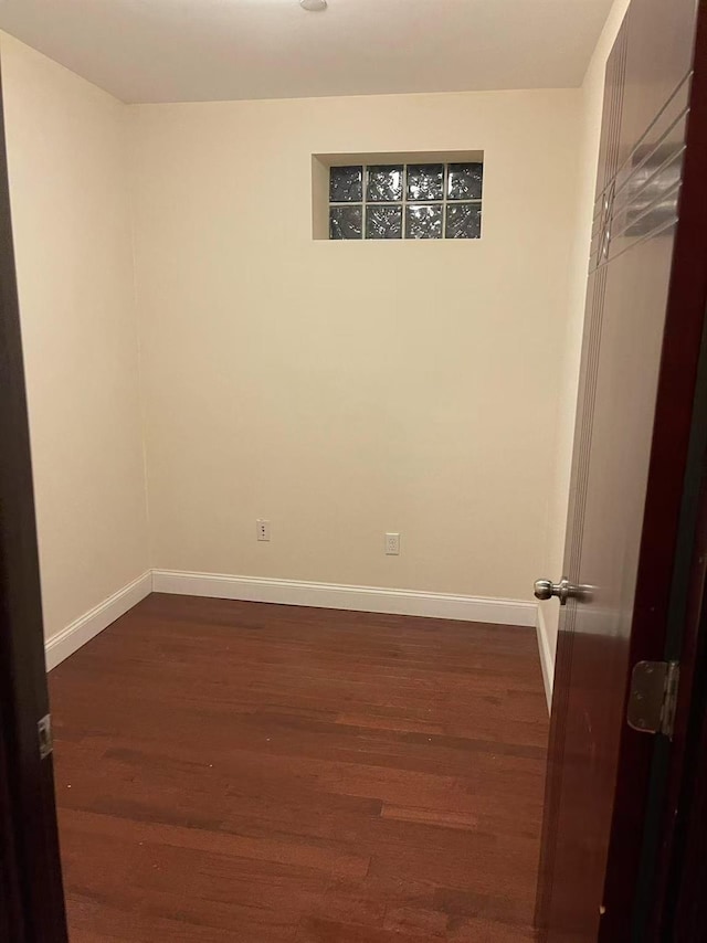 spare room with baseboards and dark wood finished floors