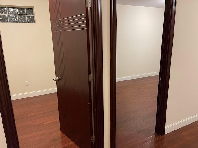 corridor with dark wood-style floors and baseboards