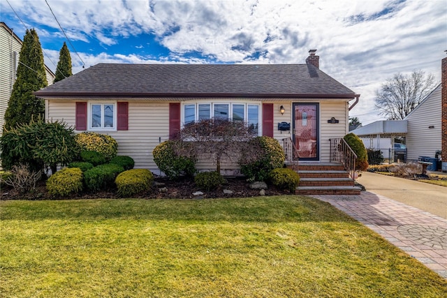 view of front of home with a front yard, roof with shingles, and a chimney