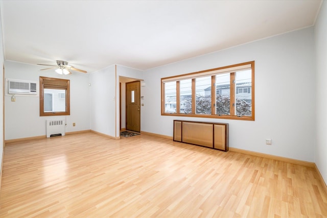 unfurnished living room featuring radiator heating unit, a wall mounted air conditioner, light wood-style flooring, and baseboards