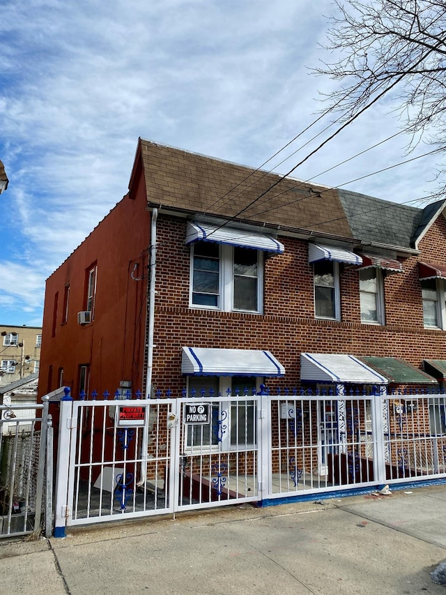 view of front facade with roof with shingles, fence, and brick siding