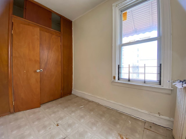 unfurnished bedroom with light floors, crown molding, baseboards, and a closet