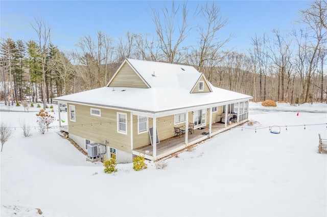 snow covered back of property with a porch