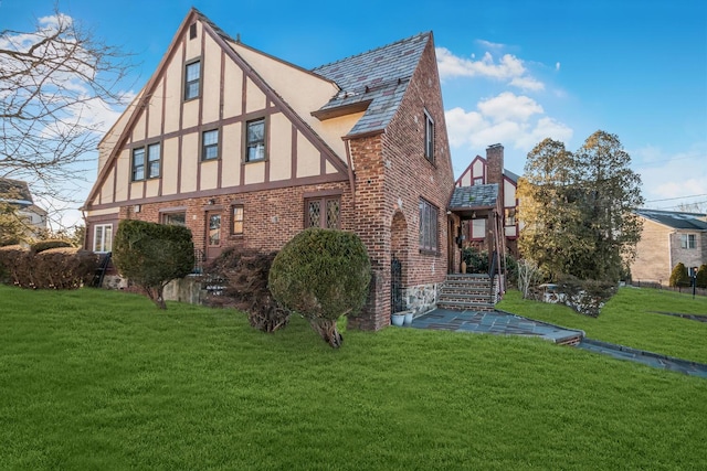 view of property exterior with brick siding, a chimney, a lawn, and stucco siding