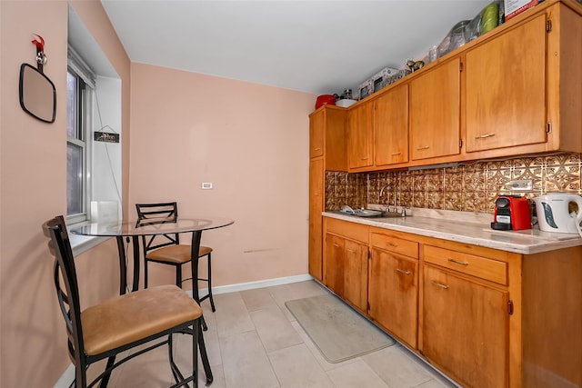 kitchen with brown cabinets, light countertops, baseboards, and tasteful backsplash