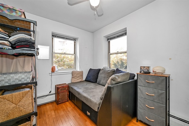 bedroom with light wood-type flooring, baseboard heating, and a ceiling fan