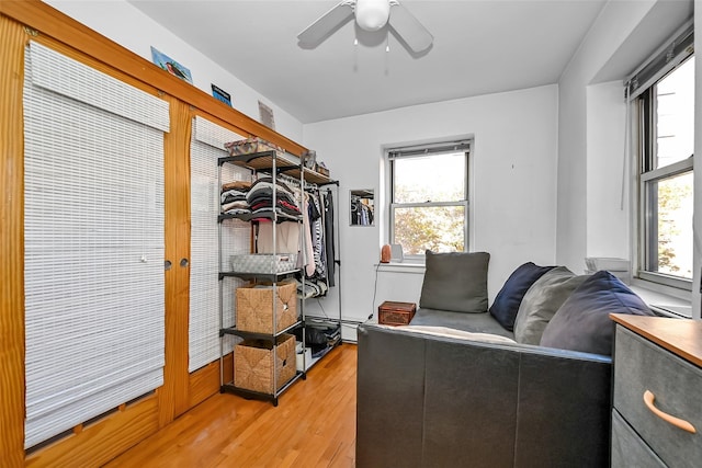 interior space with ceiling fan, a baseboard heating unit, and wood finished floors