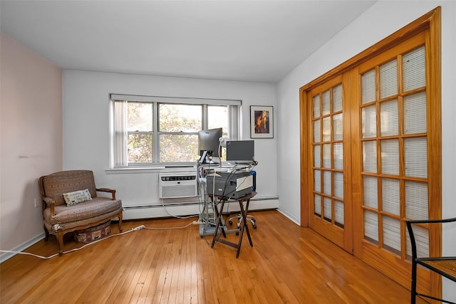 office space with an AC wall unit, baseboards, and light wood finished floors