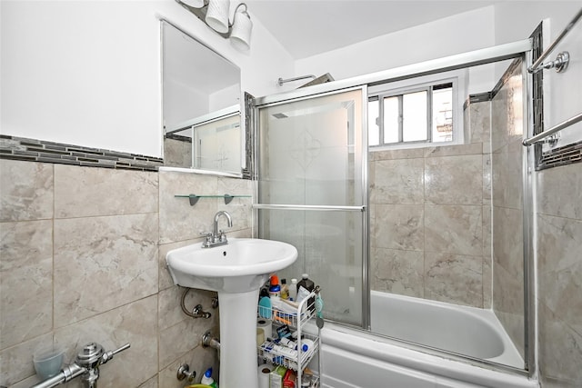 bathroom featuring combined bath / shower with glass door and tile walls