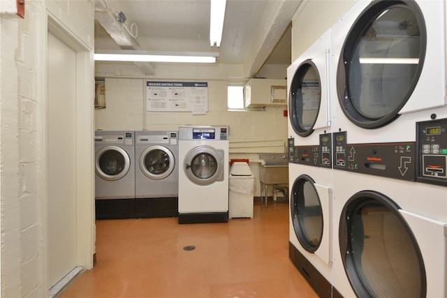 community laundry room featuring stacked washer and dryer, washer and clothes dryer, concrete block wall, and light floors