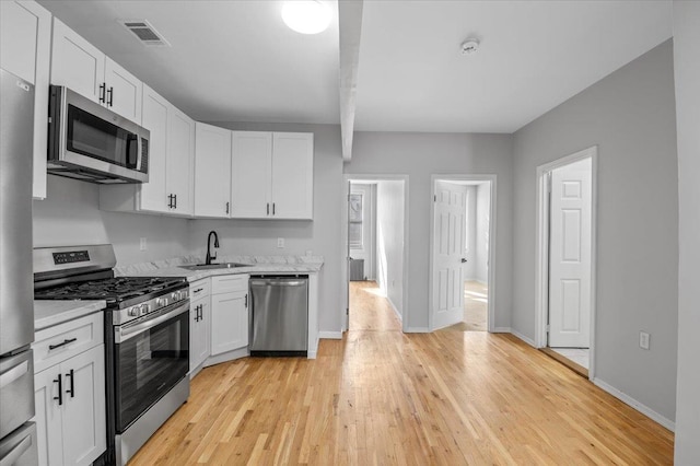 kitchen with visible vents, white cabinetry, stainless steel appliances, and a sink