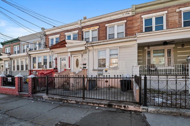 multi unit property featuring brick siding, a fenced front yard, and a ceiling fan