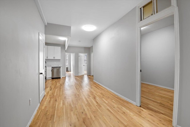 hallway featuring light wood finished floors and baseboards