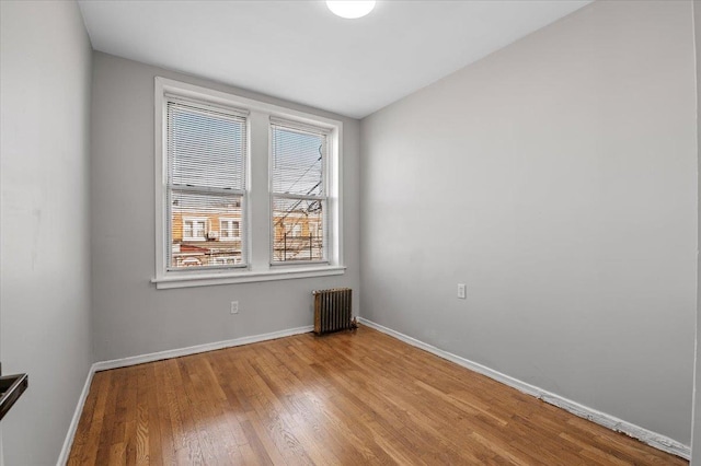 unfurnished room featuring radiator, light wood finished floors, and baseboards