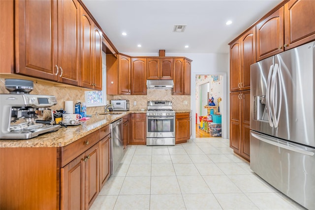 kitchen with light tile patterned floors, visible vents, appliances with stainless steel finishes, light stone countertops, and under cabinet range hood