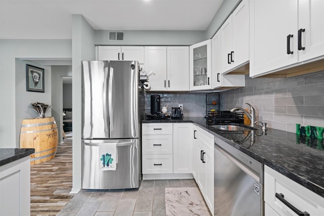 kitchen featuring visible vents, appliances with stainless steel finishes, glass insert cabinets, white cabinets, and a sink