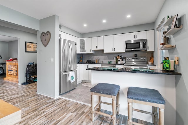 kitchen featuring glass insert cabinets, a peninsula, appliances with stainless steel finishes, and white cabinets