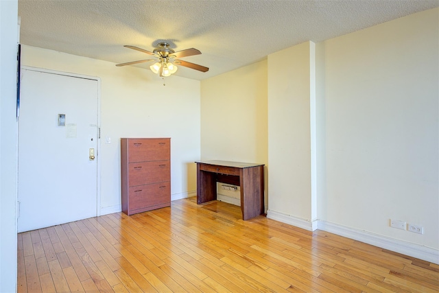 empty room with light wood finished floors, a textured ceiling, baseboards, and a ceiling fan