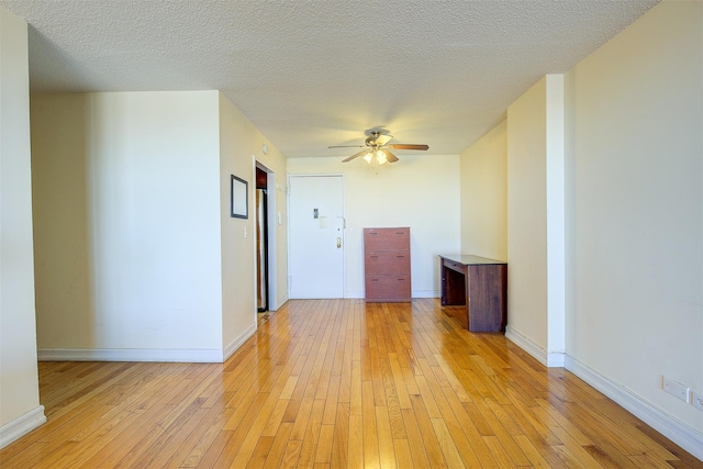 empty room featuring a textured ceiling, baseboards, a ceiling fan, and light wood-style floors