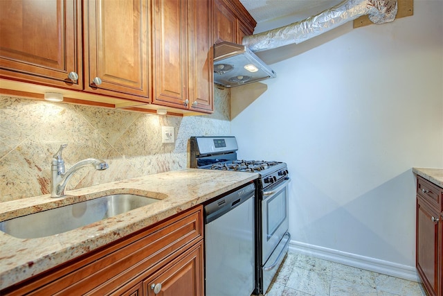 kitchen featuring appliances with stainless steel finishes, a sink, light stone counters, and baseboards