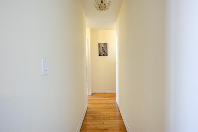 hall with baseboards and light wood finished floors