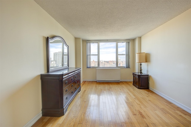 unfurnished room with light wood-style floors, baseboards, and a textured ceiling