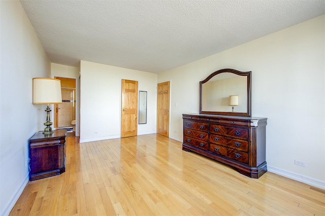 bedroom with a textured ceiling, baseboards, and wood finished floors