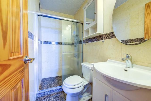 full bathroom featuring tile walls, toilet, a stall shower, a textured ceiling, and vanity